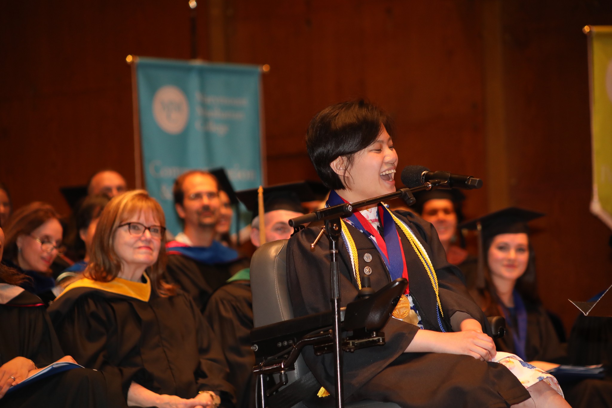 Student giving a speech at Commencement 2017; faculty members watch her from behind