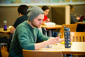 Student sitting in the Commons looking at his phone