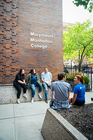 Students sitting on the ledge in the terrace talking to each other outside of Marymount Manhattan College