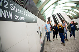Students standing in the Second Avenue Subway Station looking towards the sign that says 72nd Street & 2nd Avenue NW corner