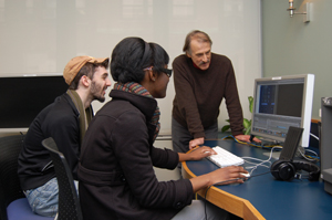 Professor of Communication Arts Alister Sanderson, Ph.D. (right) and two MMC students review a creative video project, using equipment in...